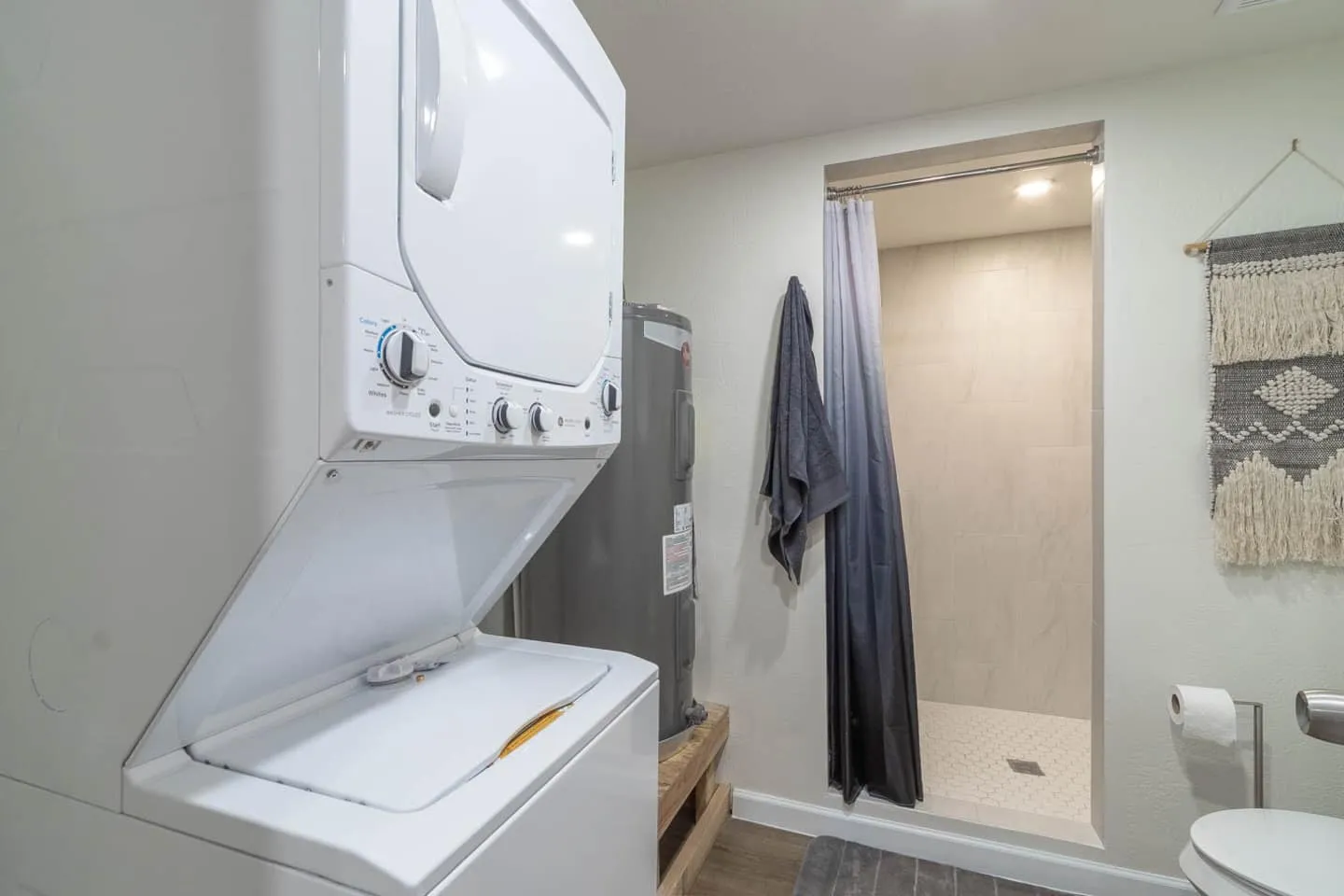 Unit 1 stacked washer and dryer next to the bathroom and shower