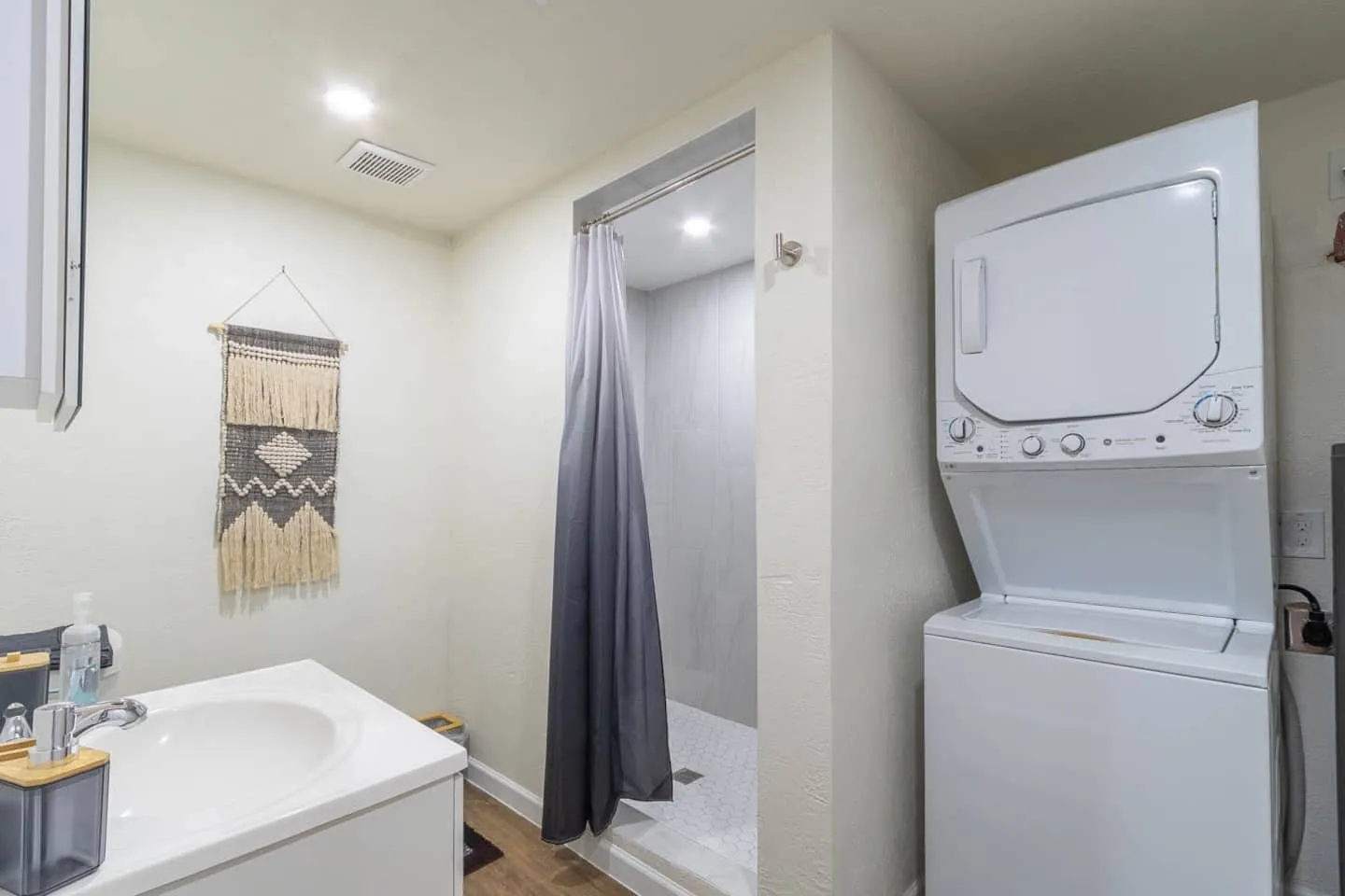 Unit 2 bathroom with a stacked washer and dryer next to the shower