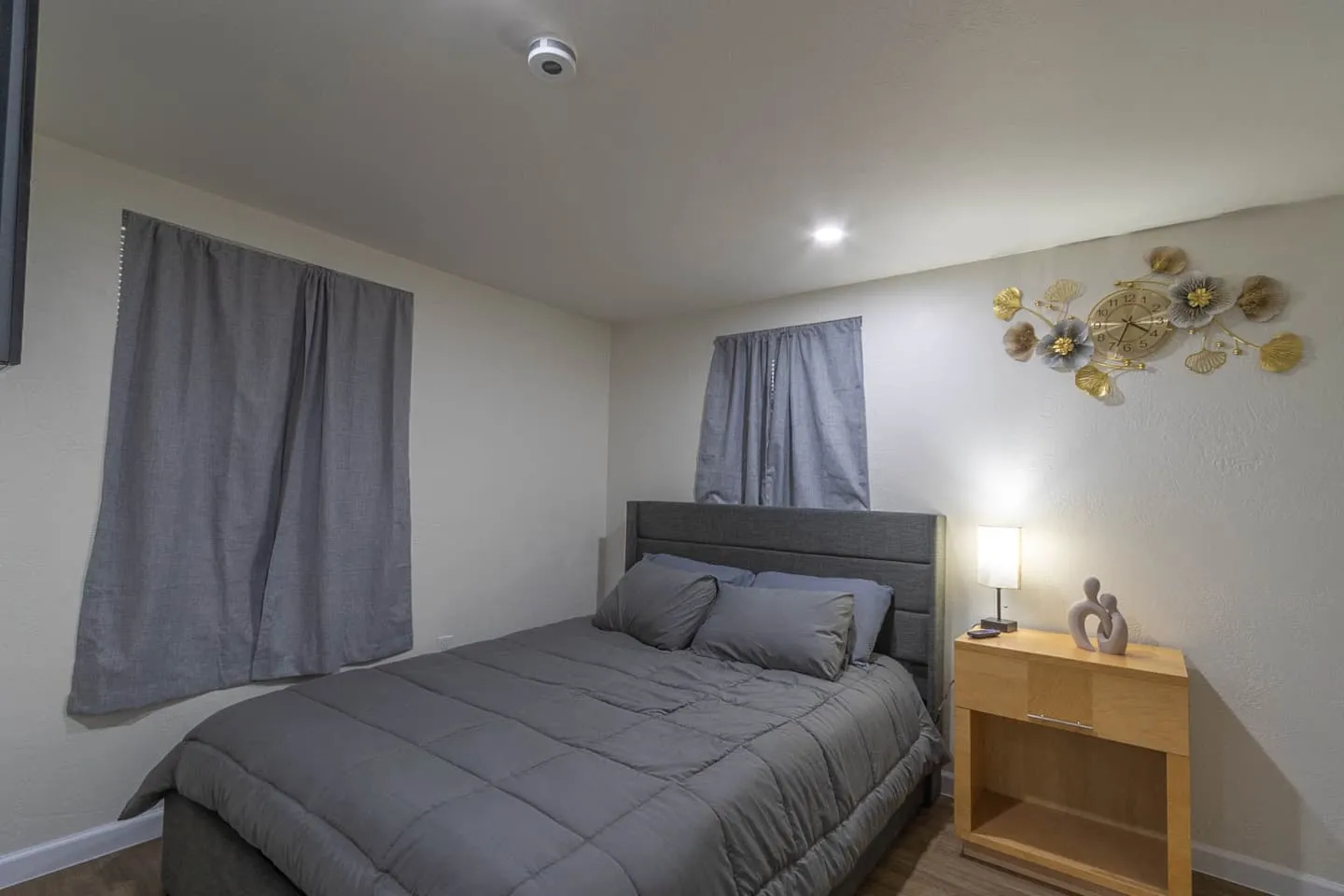 Unit 1 bedroom with a queen bed, gray bedding, nightstand and lamp