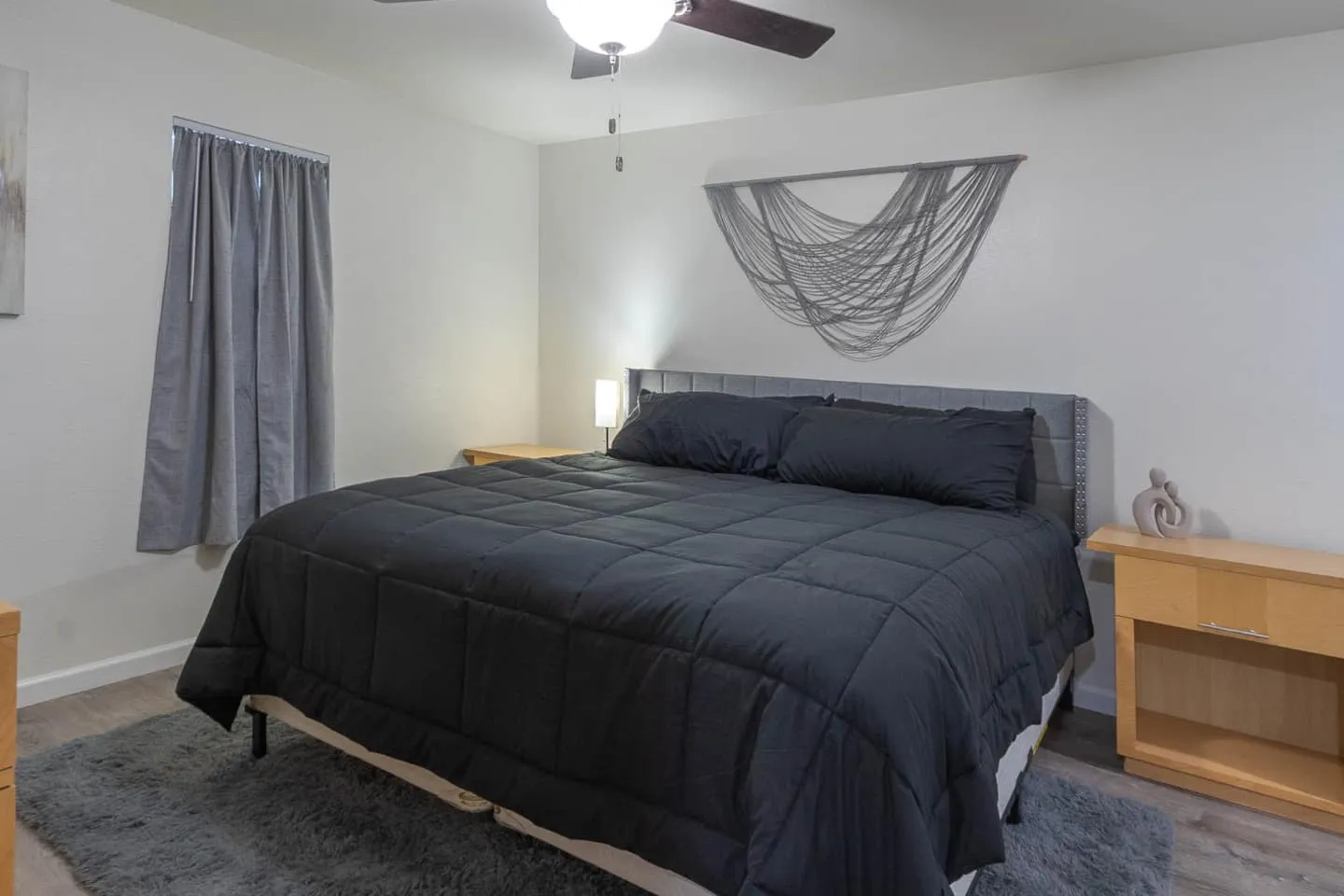 Unit 5 bedroom with a king bed, dark bedding and a ceiling fan