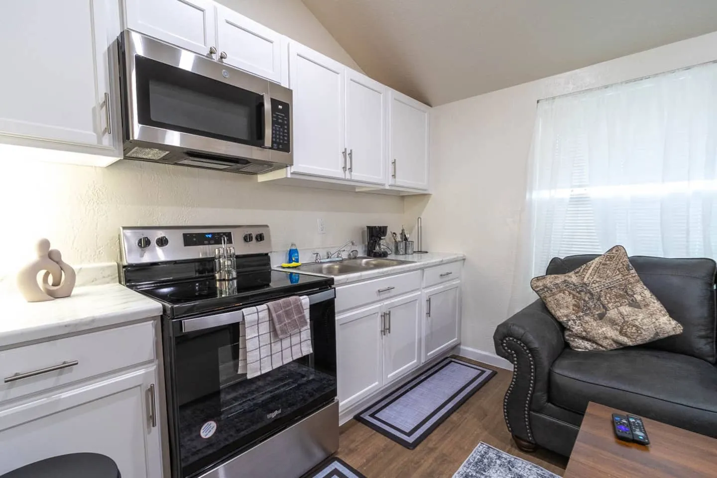Unit 4 kitchenette with a stove, microwave and white cabinets