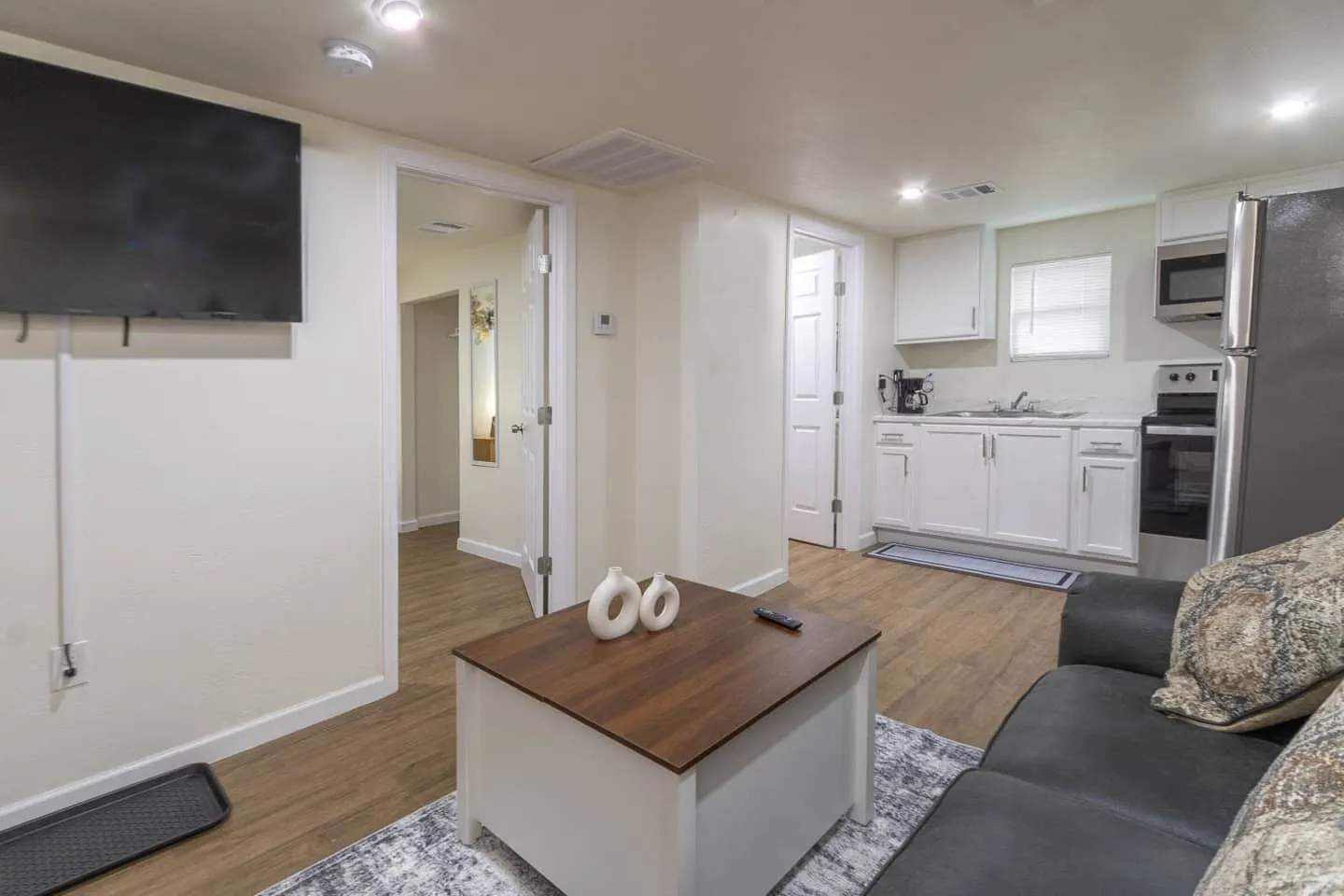 Unit 1 living room with a wall-mounted TV, looking toward the kitchen