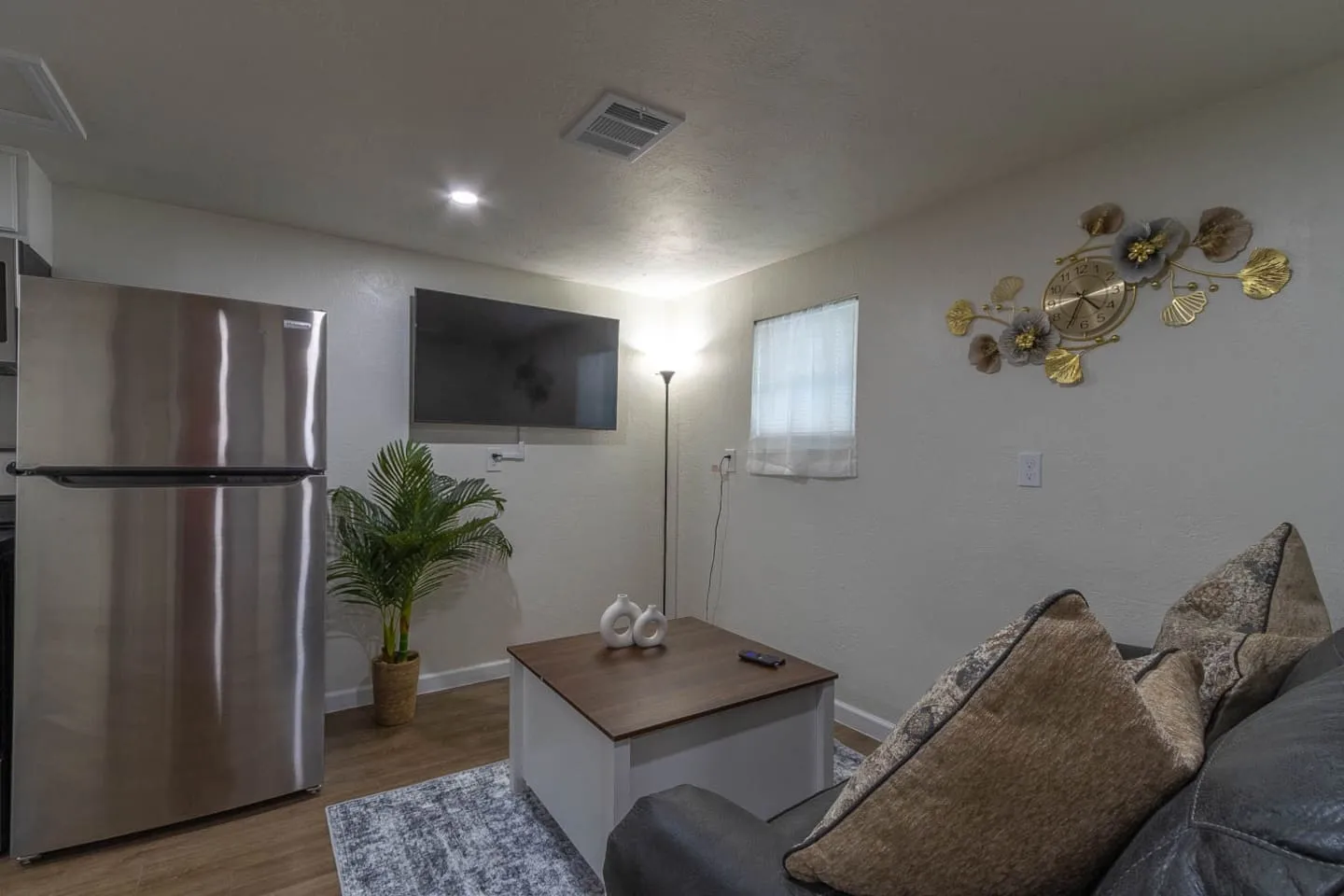 Unit 2 living room with a smart TV, gray sofa, coffee table and wall art