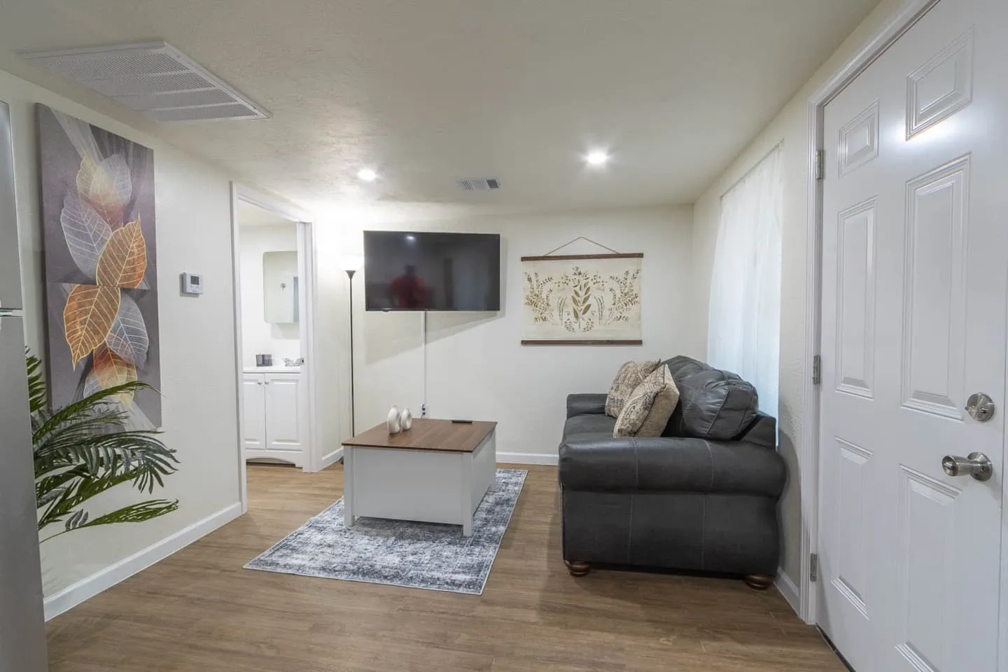 Unit 3 living room with a gray sofa, smart TV, coffee table and plant