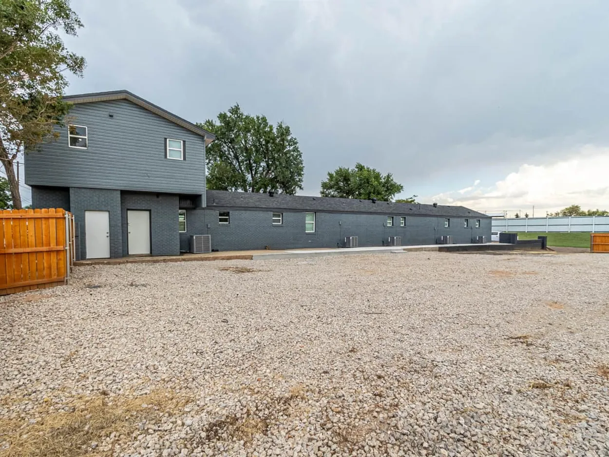 The back of the Sparra Homes building and the gravel parking area behind the units